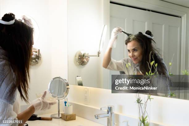 donna matura ispanica che si tinge i capelli a casa - tintura foto e immagini stock