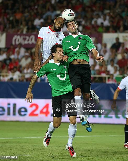 Frederic Kanoute of Sevilla heads the ball with Karim Haggui and Emanuel Pogatetz of Hannover during the UEFA Europa League Play-Off second leg match...