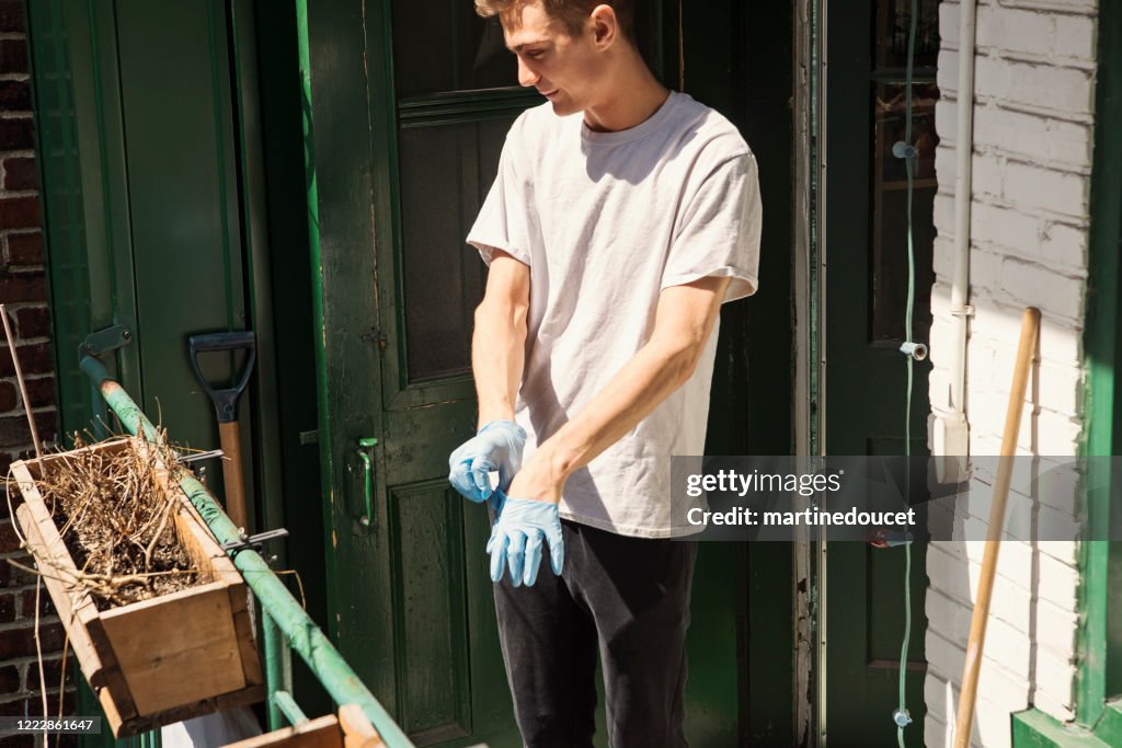Millenial man cleaning city balcony in spring.