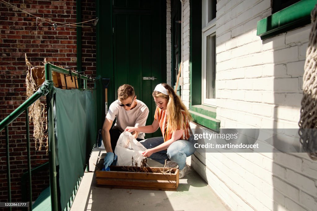 Milenial pareja de limpieza balcón de la ciudad en primavera.