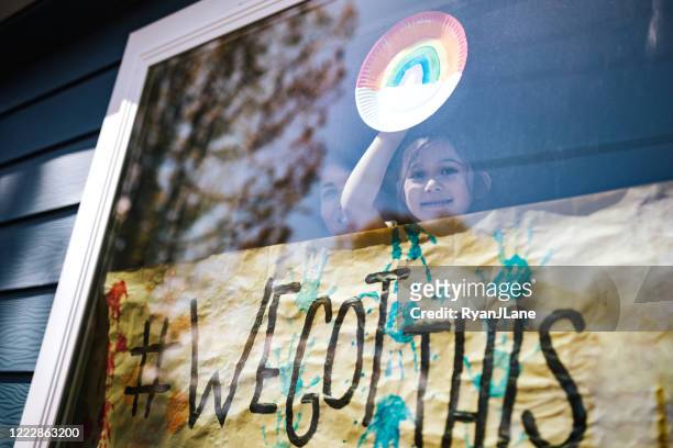 mother and daughter wave out home window with banner - waving banner stock pictures, royalty-free photos & images