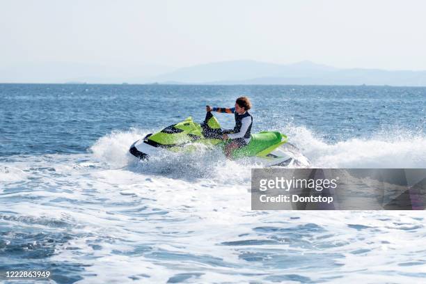 l'uomo guida la moto d'acqua gialla sul mare turchese in una giornata blu - mare moto foto e immagini stock