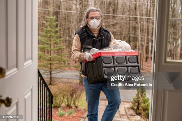 mature man carrying plastic reusable bins filled with groceries to the house - alex potemkin coronavirus stock pictures, royalty-free photos & images