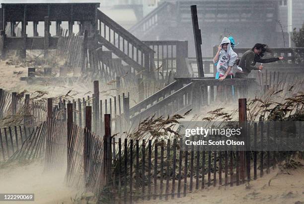 People shield themselves from blowing sand and rain as they look over the beach during Hurricane Irene August 27, 2011 in Kill Devil Hills, North...