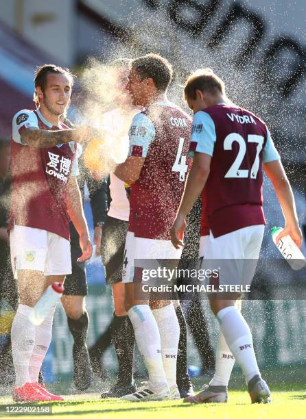 Burnley's English midfielder Josh Brownhill sprays water to Burnley's English midfielder Jack Cork during the drinks break in the English Premier...