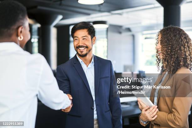 uomo d'affari sorridente che stringe la mano al collega - asian businessman happy foto e immagini stock