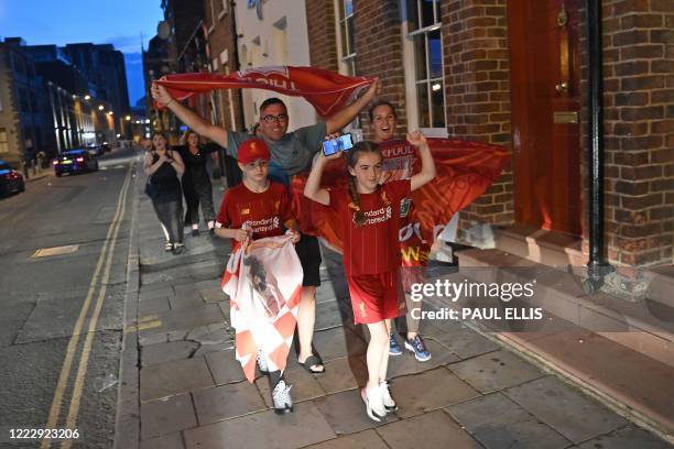 Fans celebrate Liverpool winning the championship title of the English Premier League following Chelsea's 2-1 victory over Manchester City, in...