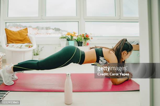 young female trying plank at home - flat stomach fotografías e imágenes de stock