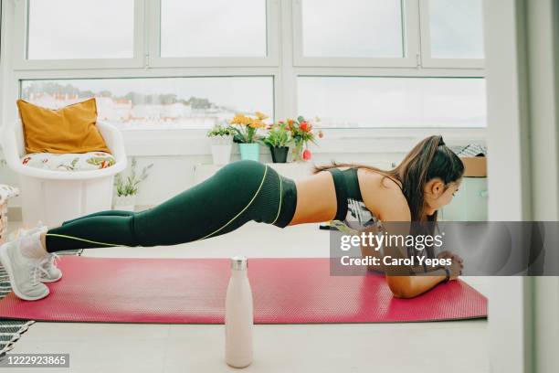 young female trying plank at home - plank exercise stockfoto's en -beelden