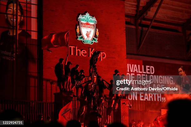 Fans climb on the gates outside the Kop as they celebrate Liverpool becoming Premier League Champions on June 25, 2020 in Liverpool, England.