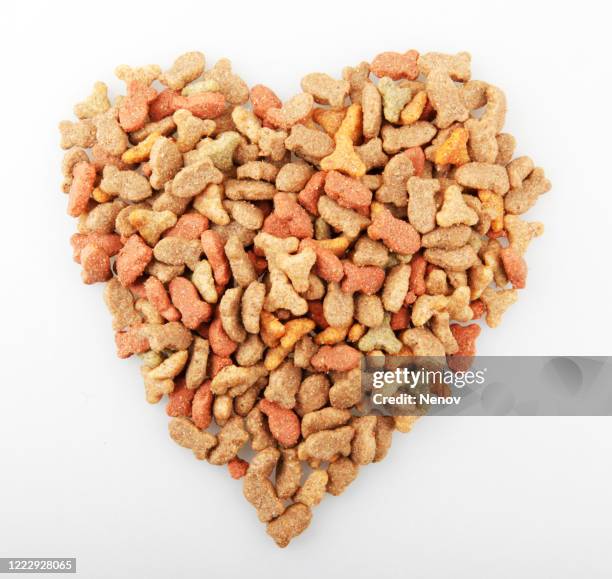 dry heart-shaped pet food isolated on a white background - cat food stock pictures, royalty-free photos & images
