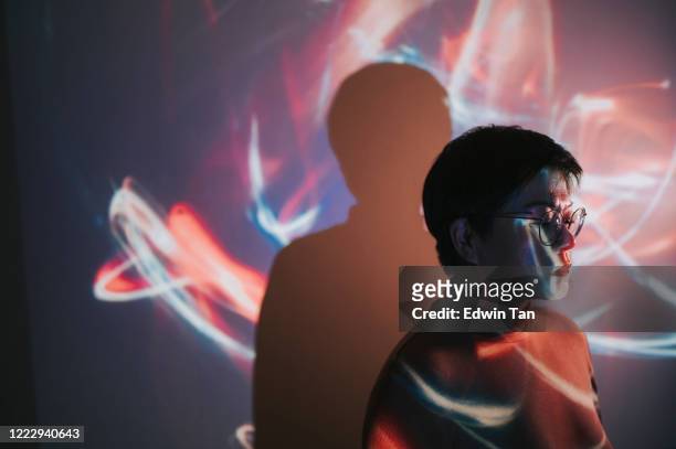 porträt der asiatischen chinesischen frau mit projektor reflektieren bild an der wand - projection stock-fotos und bilder