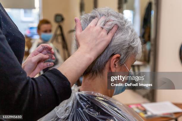 Hands stroking through the hair of a customer with a protective mask are seen on May 04, 2020 in Witten, Germany. Because of the curfew imposed by...