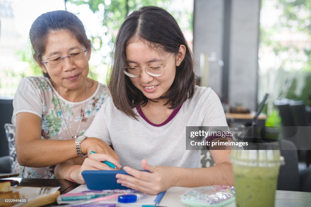 Asiatische Familie Teenager und Mutter mit digitalen Tablet und Smartphone für E-Learning zu Hause und entspannen mit Online-Shopping E-Commerce mit Kreditkarte und SMS auf sozialen Netzwerken