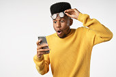 Shocked african man while watching in smartphone on isolated white background
