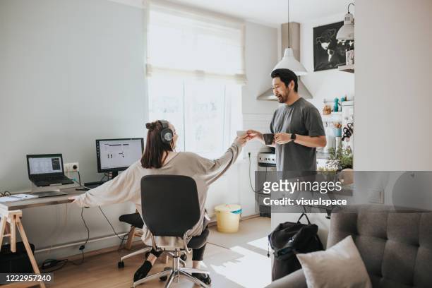 Adult man gives his wife a cup of morning coffee before work at home office