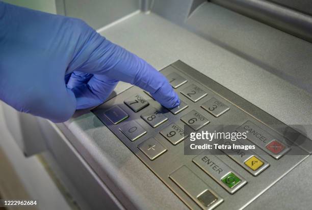 gloved hand pushing button of cash machine - push pin stock-fotos und bilder