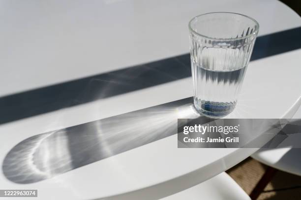 glass of water on table making shadows - translucent glass stock pictures, royalty-free photos & images