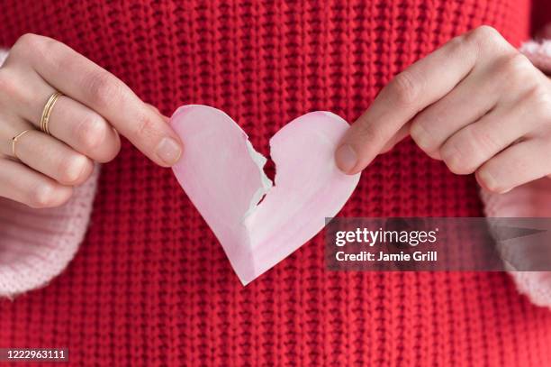 woman ripping paper heart in half - broken heart stockfoto's en -beelden