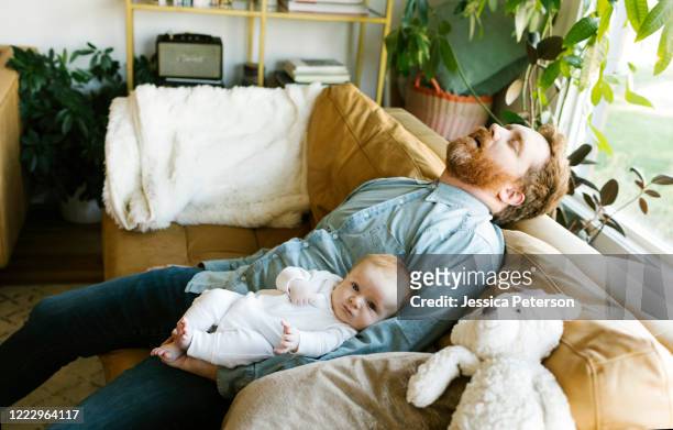 sleeping father with baby son (2-3 months) on sofa - teddy day stockfoto's en -beelden