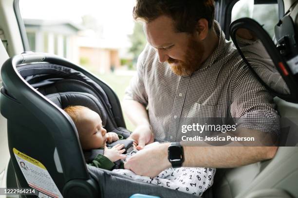 father buckling baby boy (2-3 months) in car seat - guy in car seat stockfoto's en -beelden