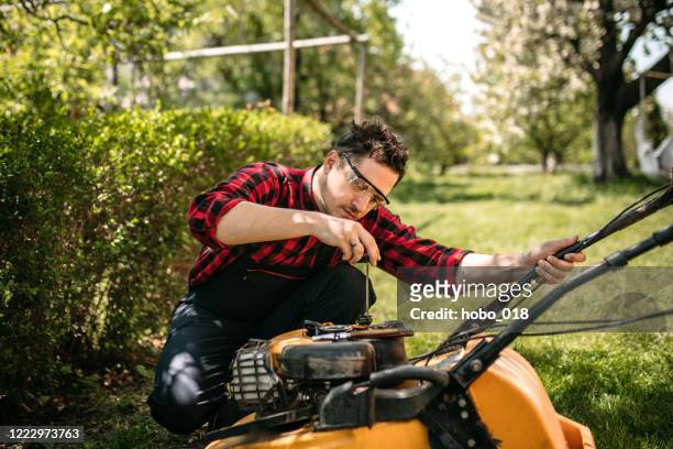 mann überprüft einen rasenmäher in seinem hinterhof - lawnmower stock-fotos und bilder
