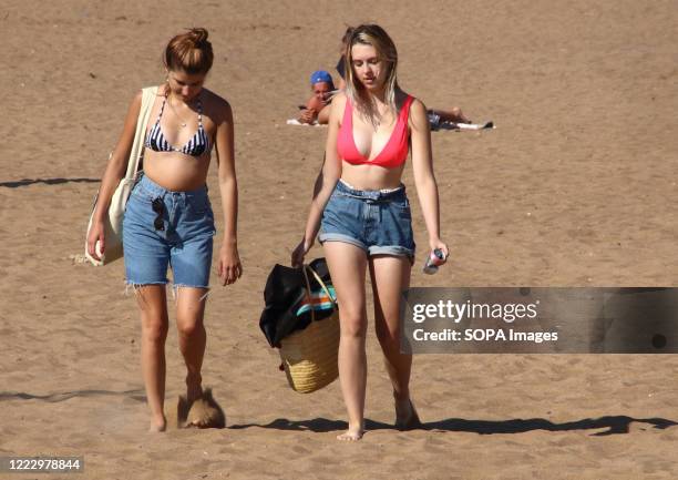 Ladies in shorts and bikini tops walk on the beach on the hottest day of the year. People head to the beach at the popular seaside resort of Skegness...