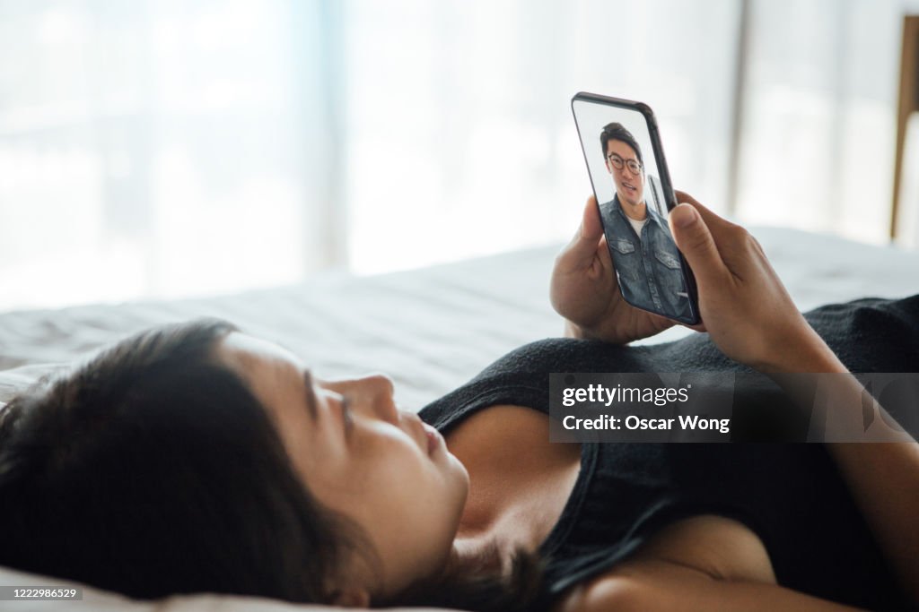 Young Woman Making Video Call With Smartphone In Bed