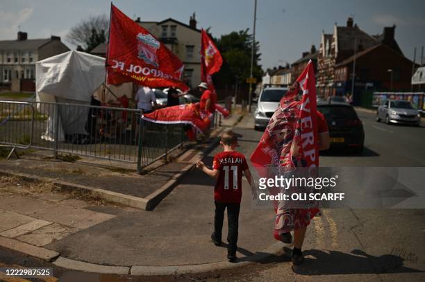 Liverpool fans carry flags as they walk away from Anfield stadium in Liverpool, north west England on June 26, 2020 after Liverpool FC sealed the...