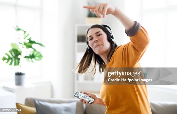 cheerful young woman with headphones indoors at home, listening to music. - yellow shirt stock pictures, royalty-free photos & images