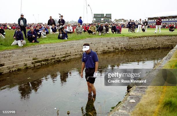 Jean Van De Velde of France looks at his ball in the burn on the 18th hole during the British Open played at the Carnoustie GC in Carnoustie,...