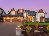 Beautiful luxury home exterior at sunset. Features three car garage and manicured lawn.