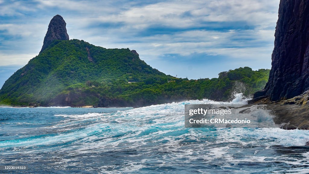 A big wave, in the background Cacimba do Padre Beach and Morro do Pico.