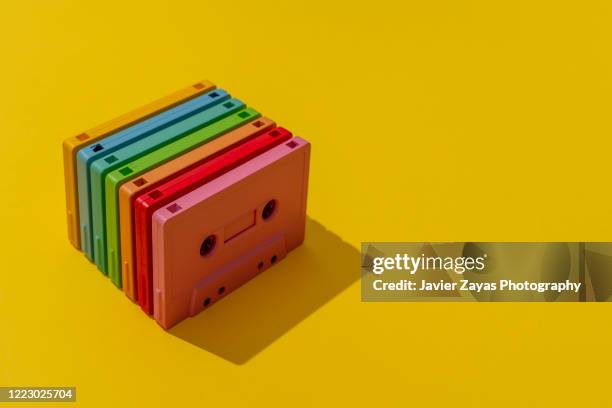 many multi colored cassette tapes on yellow background - audio cassettes photos et images de collection