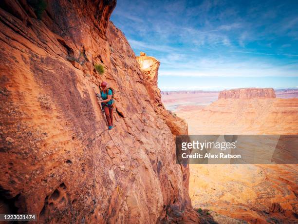 a women climbs across a narrow and exposed ledge on a southern utah desert tower - beautiful perfection exposed lady stock pictures, royalty-free photos & images