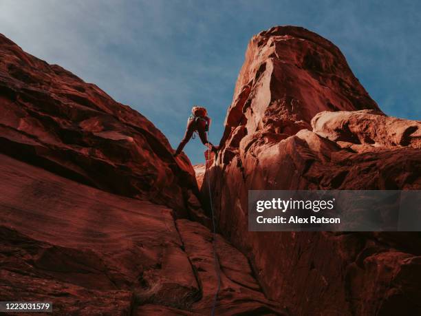 young women rappelling down a deep chimney on a desert peak - canyoneering stock pictures, royalty-free photos & images