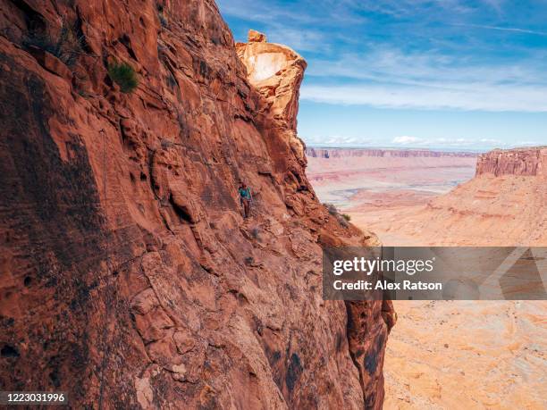 a women climbs across a narrow and exposed ledge on a southern utah desert tower - beautiful perfection exposed lady stock-fotos und bilder