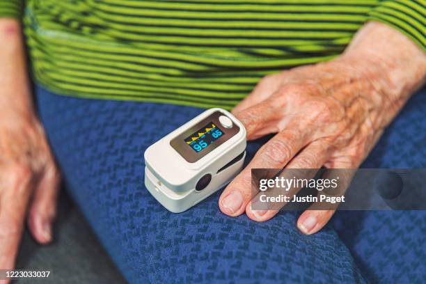 senior woman using pulse oximeter - pulse oximeter stockfoto's en -beelden