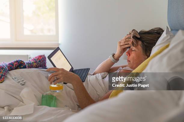 woman suffering in bed with a fever and flu like symptoms - krankheit stock-fotos und bilder