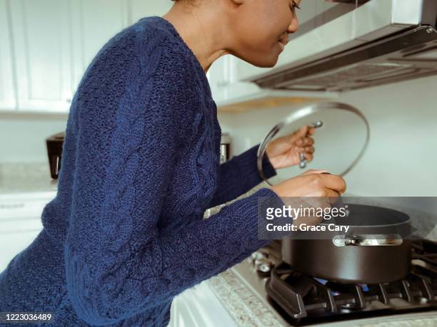 woman prepares meal over cooktop - holding saucepan stock pictures, royalty-free photos & images