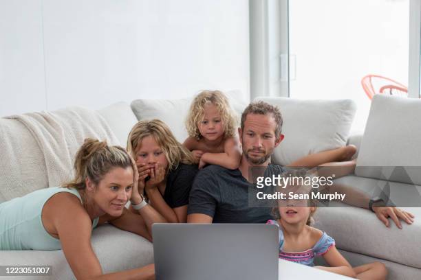 family looking at photos or video conference on laptop computer together.