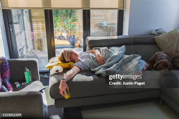 woman suffering on the sofa with a fever and flu like symptoms - covid fever stock pictures, royalty-free photos & images