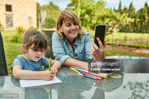 moeder en dochter tekening en het gebruik van smart phone - etui stockfoto's en -beelden