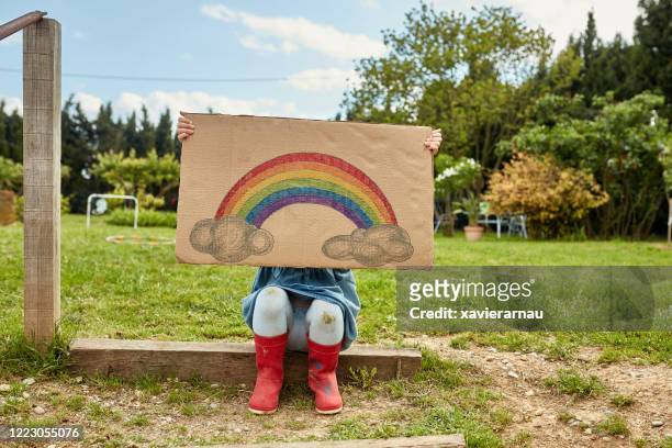 retrato de preescolar edad niña sosteniendo arco iris signo de esperanza - real estate sign fotografías e imágenes de stock