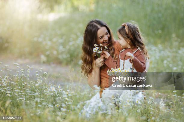 glückliche mutter und kleines mädchen, das blumen pflücken - kind blume stock-fotos und bilder