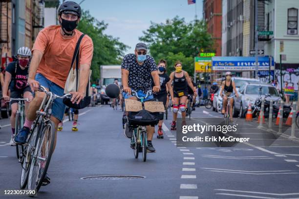 Cyclist holding a Fund Schools Not Cops sign at the bike ride. Hundreds of cyclists congregated at Maria Hernandez Park in Bushwick for a Black Lives...