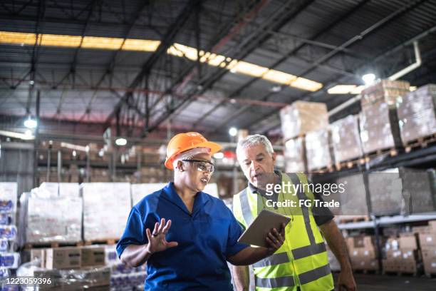 coworkers on a meeting at warehouse - warehouse safety stock pictures, royalty-free photos & images