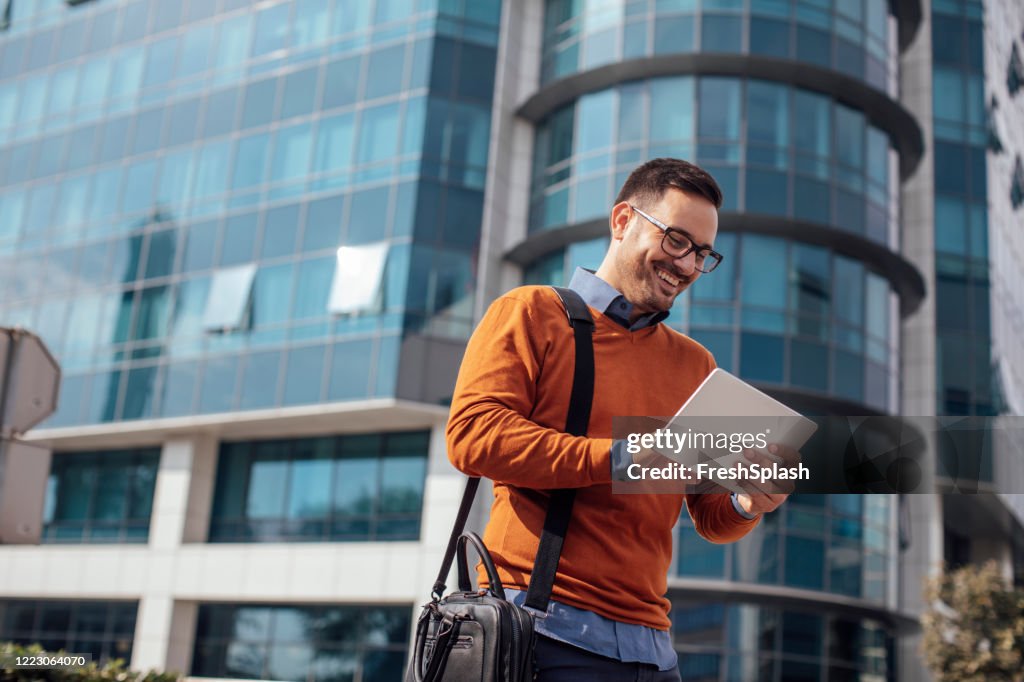 Successful Modern Young Businessman Using a Digital Tablet on the Street