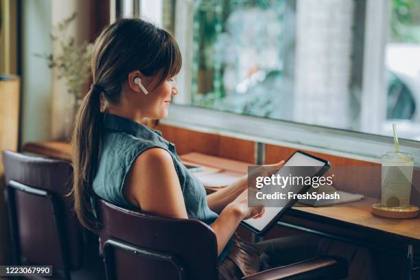 travailler dans un café: freelance designer écouter de la musique et dessiner sur sa tablette - ornement auriculaire photos et images de collection