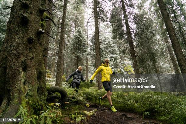 young couple trail run through a forest with fresh snow - black forest germany stock pictures, royalty-free photos & images